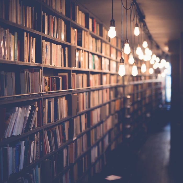 Bookshelves in a library, lit by hanging bulbs